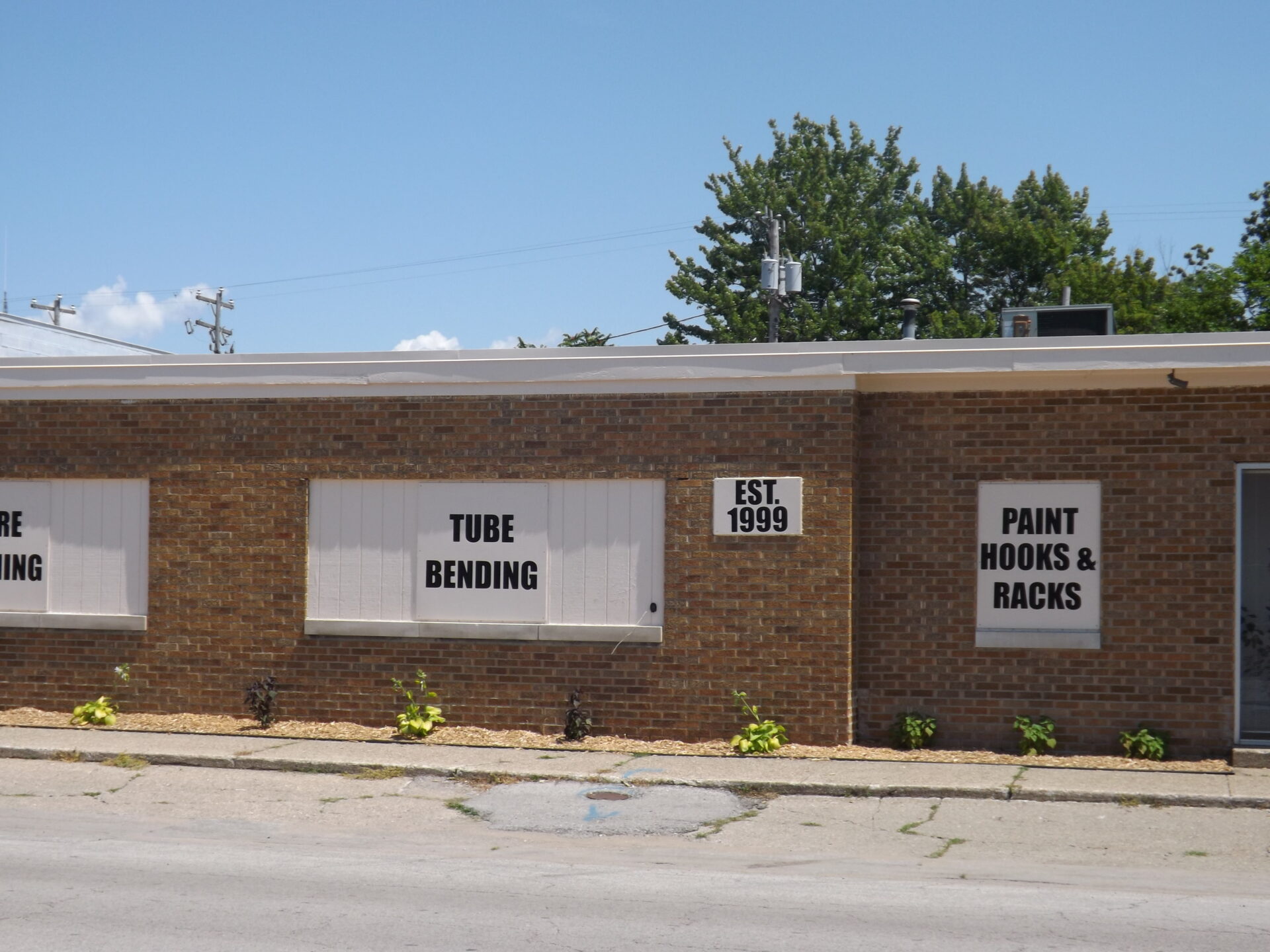 Exterior of West Michigan Tube & Wire Building with signage saying Tube Bending, Est. 1999, Paint Hooks & Racks
